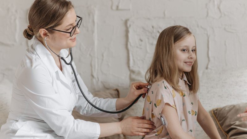 A doctor uses a stethoscope during a check-up with a young girl in a medical setting. — Comprehensive Care Provided by Online