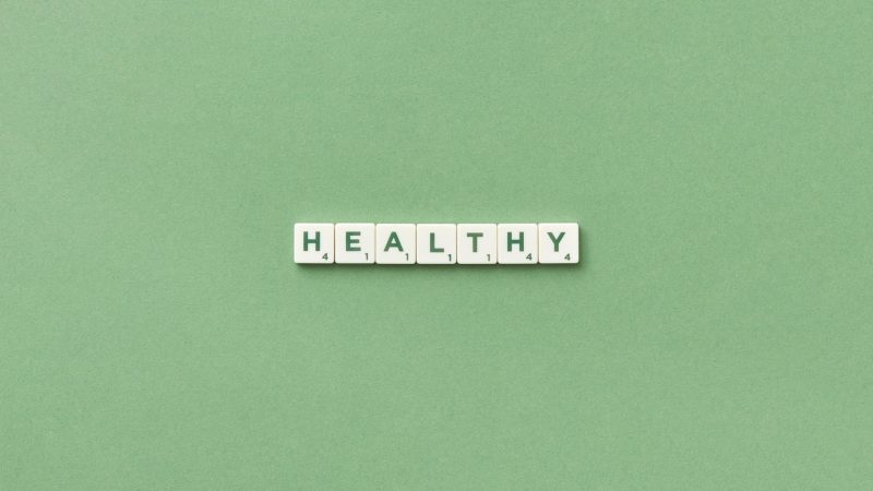 Scrabble tiles spelling the word 'healthy' on a light green background, top view. — HHA Certification Equips Caregivers With 