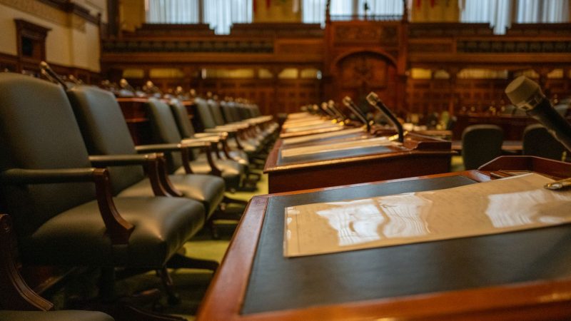 A detailed view of an empty legislative chamber with rows of desks and microphones, evoking governance. — How to Navigate the