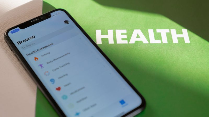 Close-up of a smartphone displaying a health app on a green surface with 'HEALTH' text. — Marketplace Health Insurance: Premi
