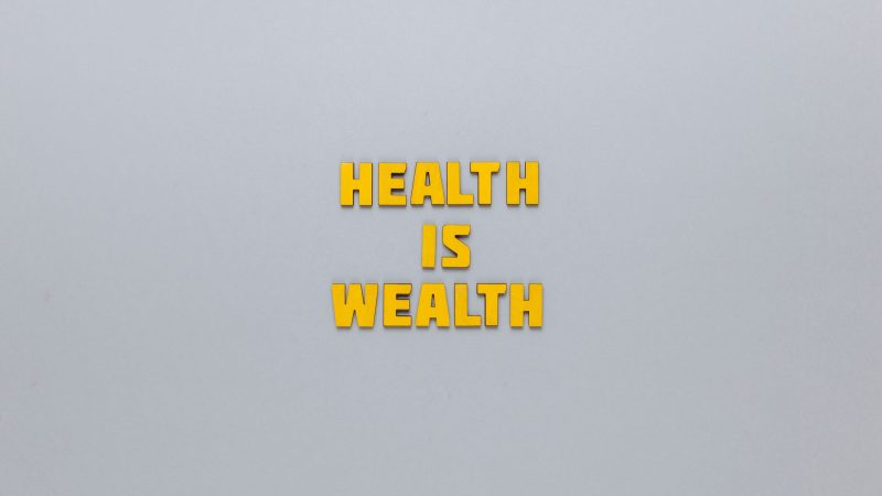 Inspirational phrase 'Health is Wealth' in bold yellow letters on a neutral gray background. — Pharmaqo Labs Supplements: Wha